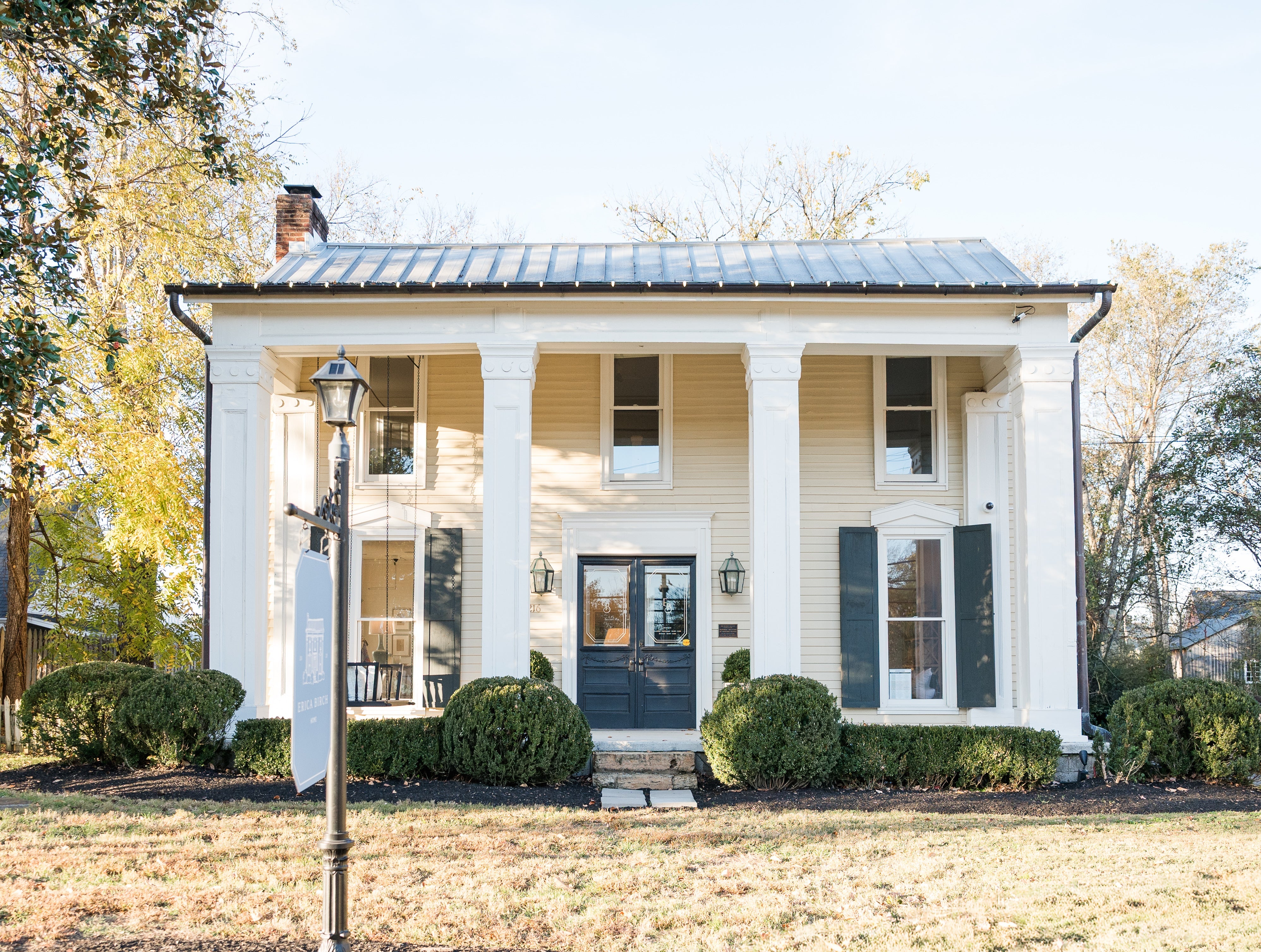 White colonial-style house with black shutters on a sunny day