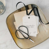 Scissors and vintage-style cards on a metallic tray with a neutral background